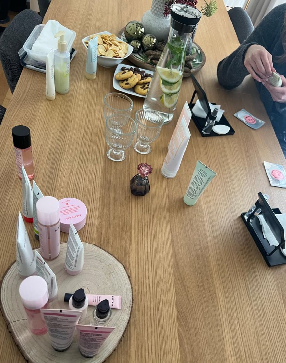 Tisch mit Zitronenwasser, Keksen und Pflegeprodukten auf einem Holzbrett